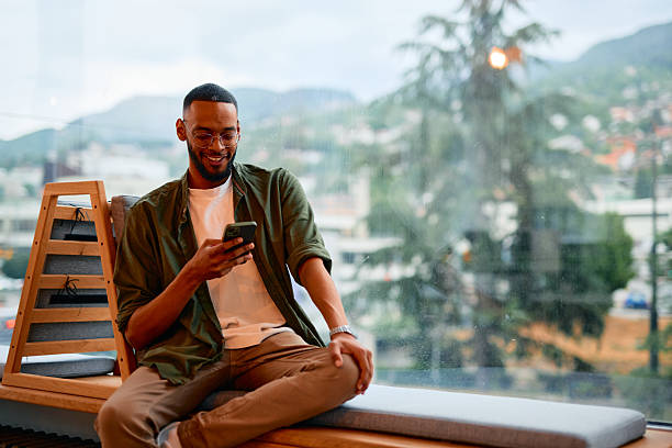 istock Young businessman using smartphone and smiling while sitting next to window 2222963883