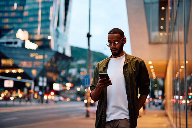 istock Young man using smartphone while walking in city at dusk 2222963910