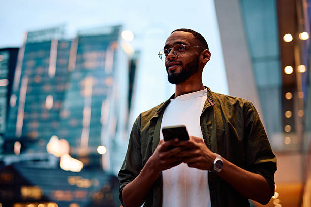istock Young businessman looking away while using smartphone in city at dusk 2222963912