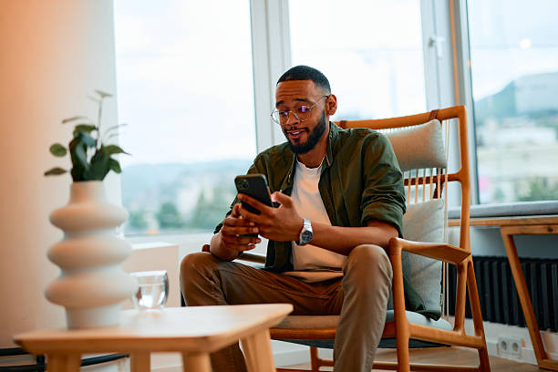 istock Young businessman using mobile phone while sitting in armchair in modern office 2222963944