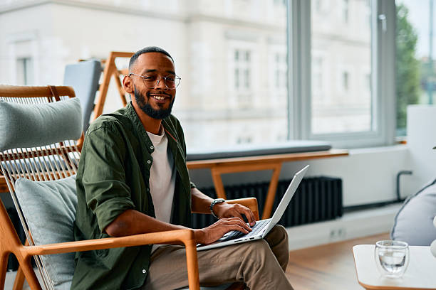 istock Young businessman working on laptop and smiling in modern office 2222964121