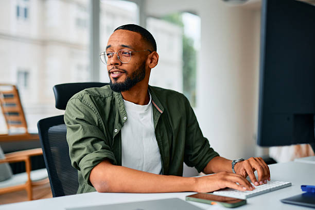 istock Young businessman typing on keyboard and looking away in modern office 2222964160