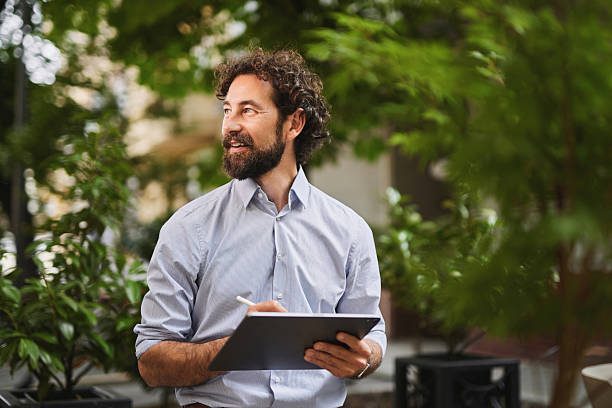 istock Businessman working with tablet and pen outdoors in a green area 2222971825