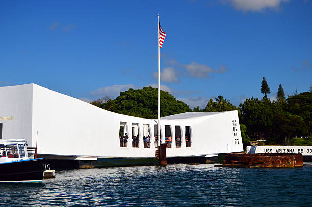 HONOLULU, HAWAII - JANUARY 10, 2026: The rusted circular barbette of the USS Arizona battleship rests above the water's surface in Pearl Harbor. This historic site at the World War II Valor in the Pacific National Monument honors the sailors lost during the December 7, 1941 attack. The background shows the modern city skyline of Oahu under a bright blue sky.