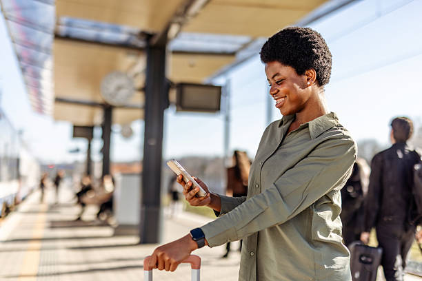 istock Smiling Woman Using Smartphone at Train Station While Traveling 2222983062