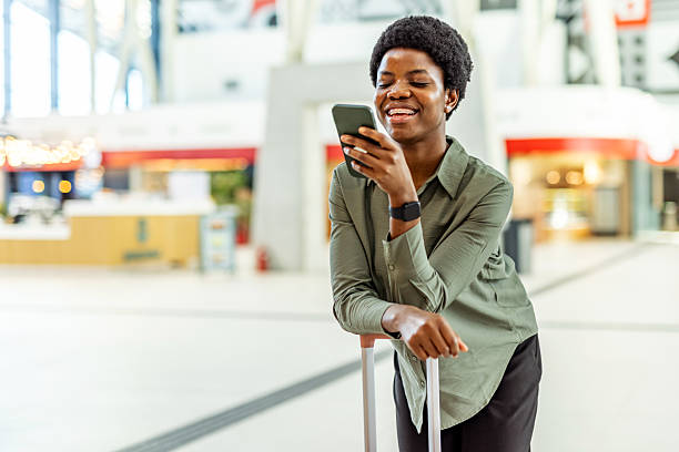istock Smiling Woman Using Smartphone in an Airport Setting 2222983092