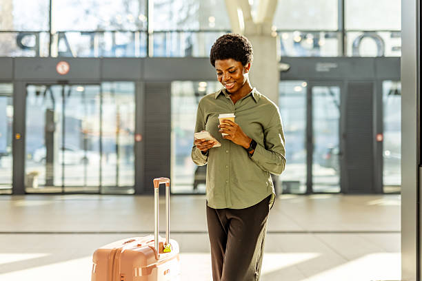 istock Traveler Smiling While Using Smartphone and Holding Coffee in a Modern Airport 2222983099