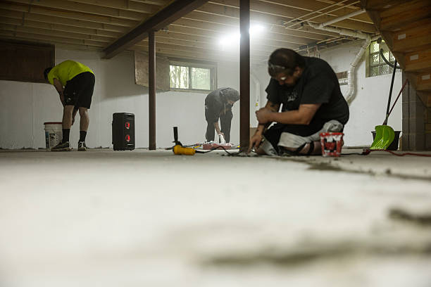 istock Team of workers doing basement waterproofing. Sealing cracks in the basement floor. Construction worker sealing cracks with hydraulic cement for waterproofing. The focus is on the group in the backdrop, while the worker in the foreground is defocused. 2222984317