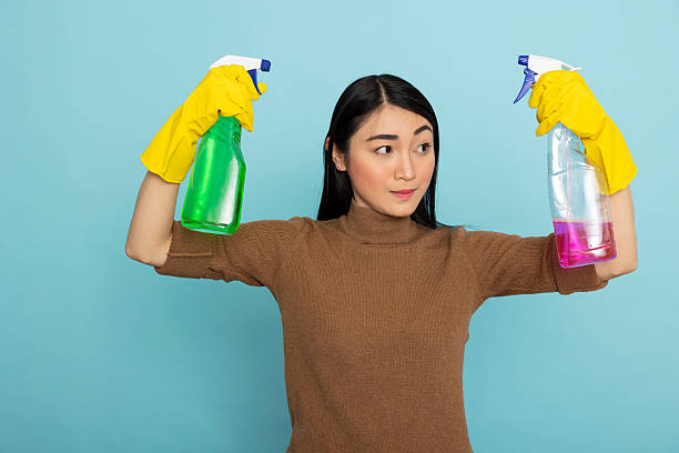 istock Housekeeper holds colorful cleaning spray bottles 2222987301