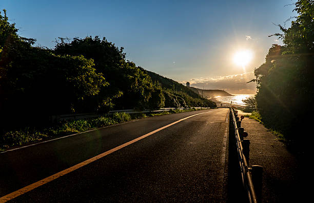 A straight road along the sea at dawn.