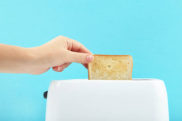 istock Toaster and female hand with toast on blue background 2222998218