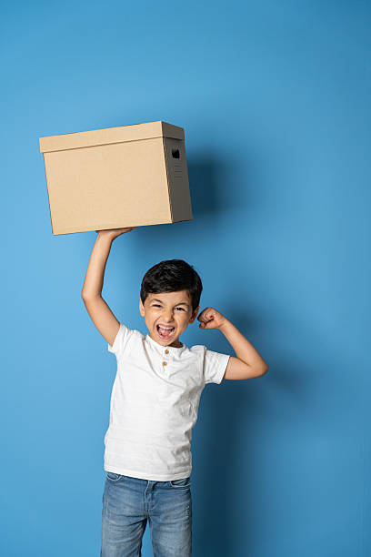 Teenage boy holding blank cardboard box over isolated yellow background, delivery concept