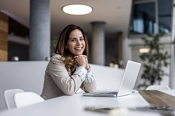 istock Businesswoman smiling at camera while working on laptop in office 2223009525