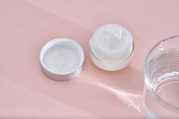 istock An open jar of cream with its texture on a pink background. 2223009841