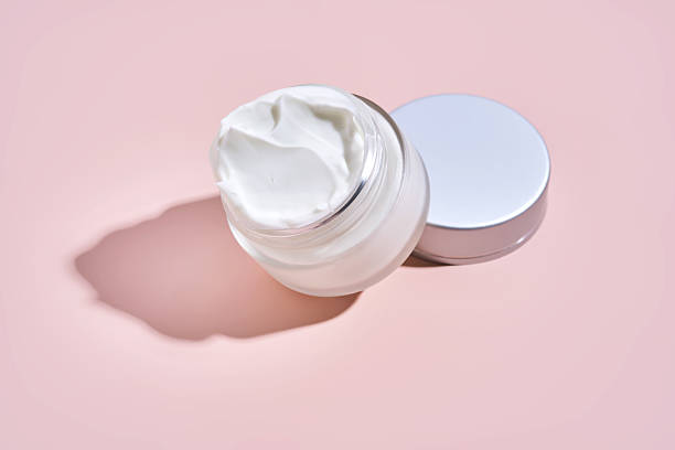 istock An open jar of cream with its texture on a pink background. 2223010137