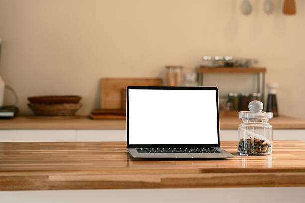 istock Blank screen laptop placed next to a jar on a wooden kitchen counter 2223011485