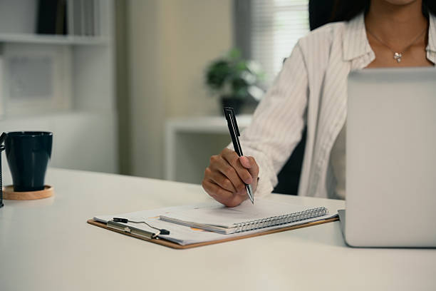 istock Businesswoman taking notes and working on laptop at modern workplace 2223011713