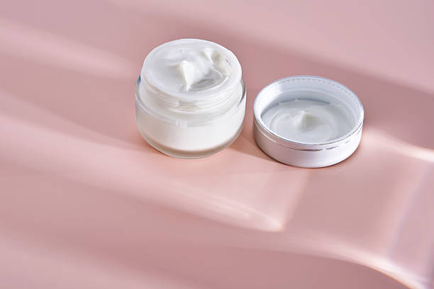 istock An open jar of cream with its texture on a pink background. 2223012153