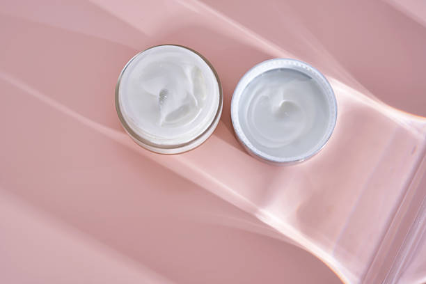 istock An open jar of cream with its texture on a pink background. 2223014441