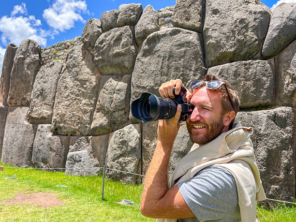 istock Smiling man holding camera and taking photo near ancient stone wall 2223016863
