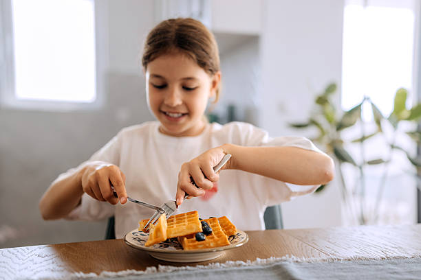 istock Girl eating blueberry waffle at home 2223021189