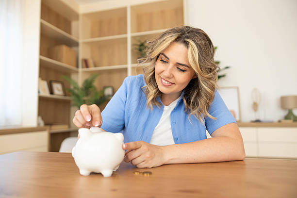 istock Adding Coins to Piggy Bank Smiling 2223028649
