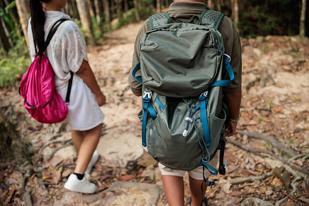 Mother and son exploring and walking through the forest with hiking backpacks in Nacional park in Koh Phangan, Thailand.