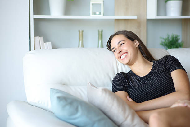 istock Happy woman sitting on a sofa at home laughing 2223032248