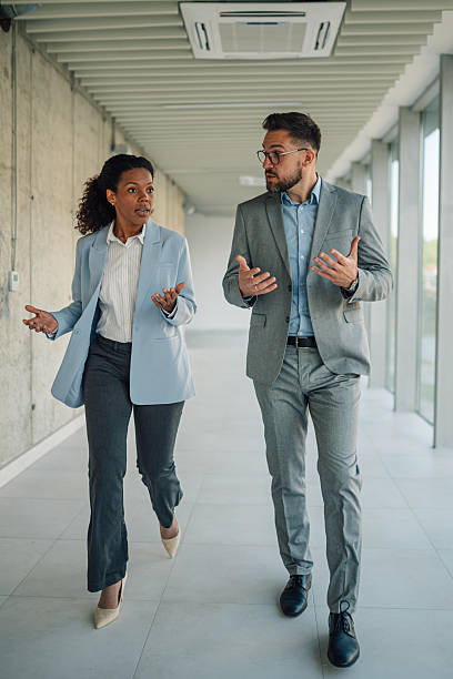 istock Businesspeople walking and talking in office hallway 2223035934