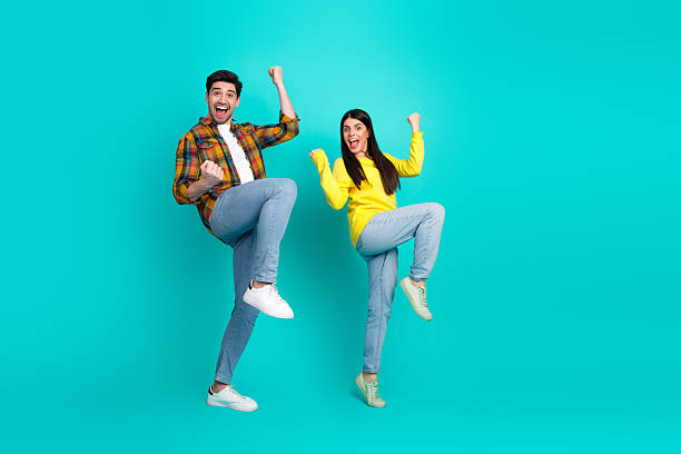 istock Cheerful young couple celebrating and posing energetically on a bright turquoise background representing joy and friendship 2223037673