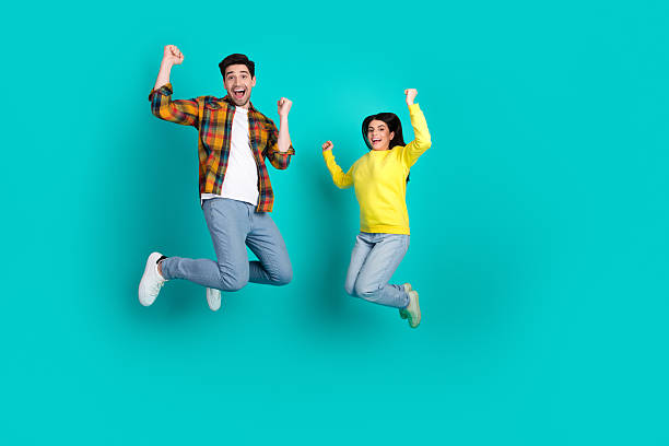 istock Young joyful couple jumping together against teal background expressing enthusiasm and happiness, celebrating positive moments 2223037708