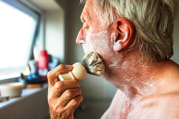 istock Senior man applying shaving cream to face using brush 2223038039