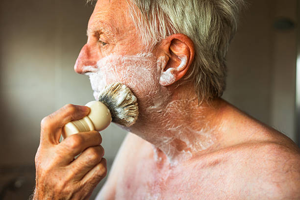 istock Senior man applying shaving cream to face using brush 2223038055