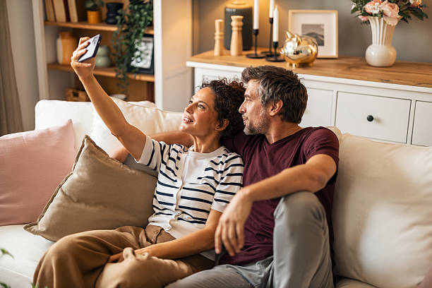 istock Couple Relaxing on Sofa Taking a Selfie Together 2223041317