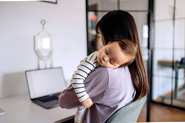 istock Woman holding baby while working on laptop at home 2223042255