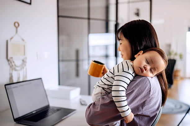istock Woman holding baby while working on laptop at home 2223042264