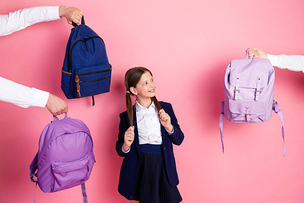 istock Happy student in school uniform surrounded by colorful backpacks on a pink background, representing education 2223042362
