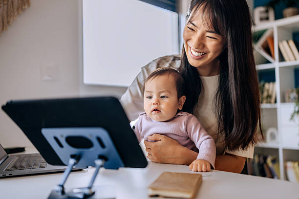 istock Busy mom holding baby and using laptop at home office 2223042375