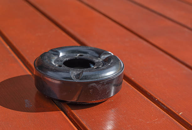 A sleek black ashtray is prominently displayed on a beautifully crafted wooden table, showcasing the elegance of hardwood and its rich wood stain finish