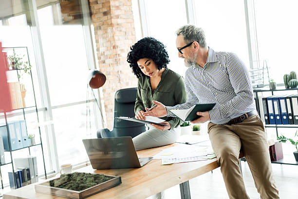 istock Two diverse business professionals collaborating on a project in a modern office environment with open workspace design 2223043558