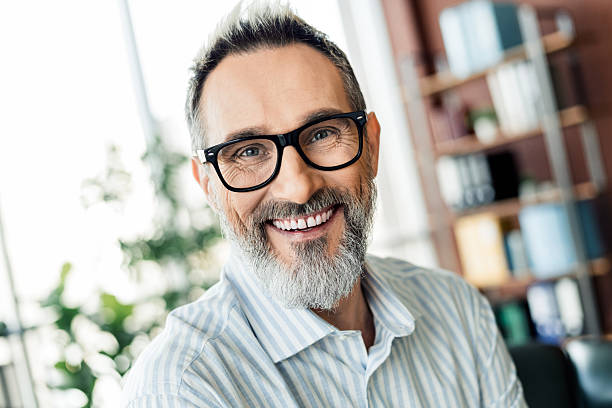 istock Confident middle-aged professional in glasses with a friendly smile, office interior background 2223043579