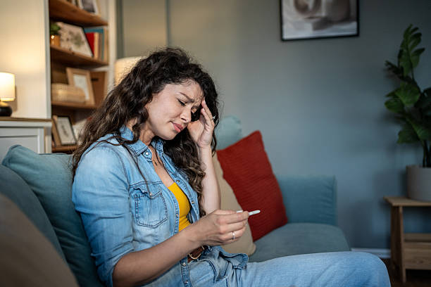 istock Sick young woman checking her temperature on the sofa 2223044259