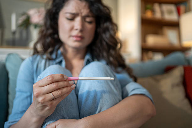 istock Sad young woman looking at negative pregnancy test at home 2223044457