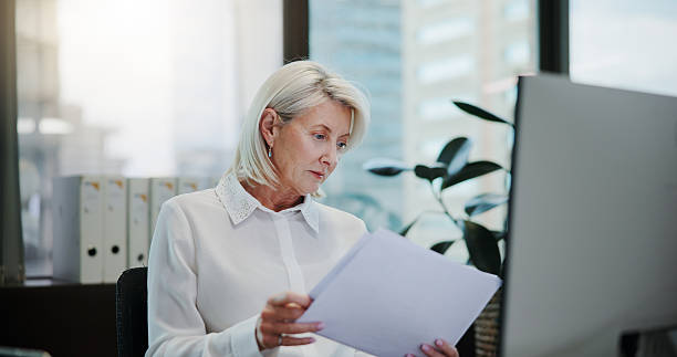 istock Documents, research and reading with business woman in office for client invoice, account payroll and portfolio report. Feedback, finance statements and capital profit with mature person for planning 2223044873