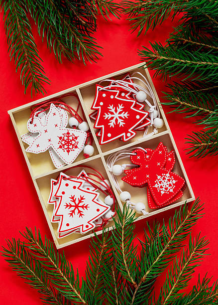 istock Christmas composition with gift box. Box with red and white Christmas tree toys - tree and angels. Wooden toys and fir tree branches on a red background. Top view. 2223044980