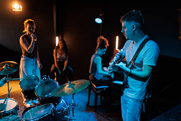 A full band, featuring a drummer, guitarist, vocalist, pianist, and cajon player, performs together on stage, creating a beautiful energy that flows between them.