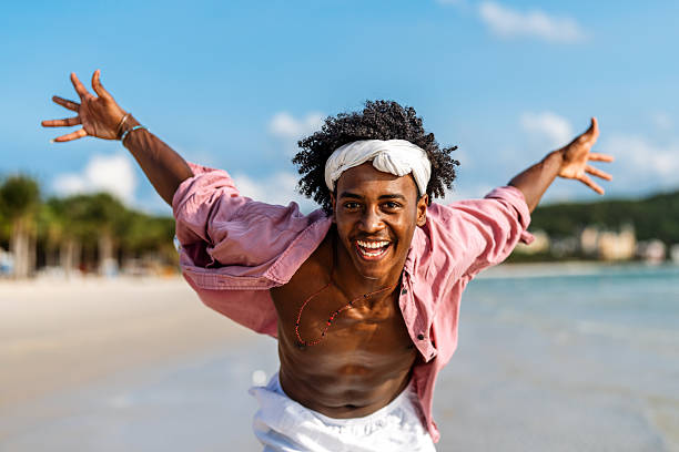 istock Young Black man enjoying a sunny beach day, running through ocean waves, smiling and feeling free 2223048955