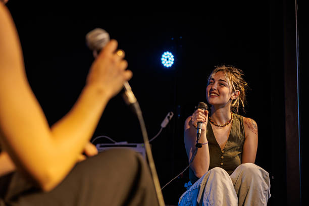 A lively group of friends celebrates at a summer music festival, dancing and clapping together. Their joyful expressions showcase the excitement of the performance under the evening sky.