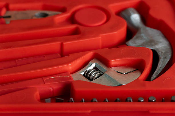 A detailed close-up image of various hand tools neatly arranged in a bright red plastic case, highlighting metallic textures and organized compartments