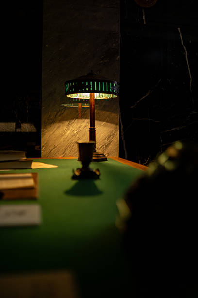 Lamp Illuminates a Desk With Scattered Papers and an Inviting Atmosphere at Night in a Stylish Interior Space